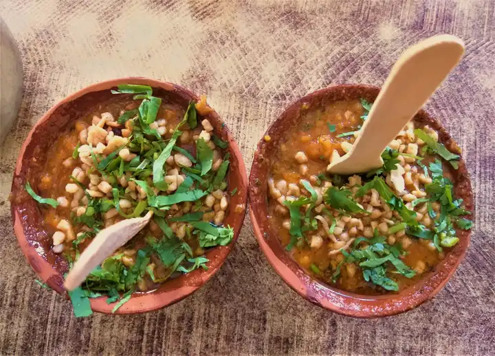 Two clay bowls of tamatar chaat topped with coriander