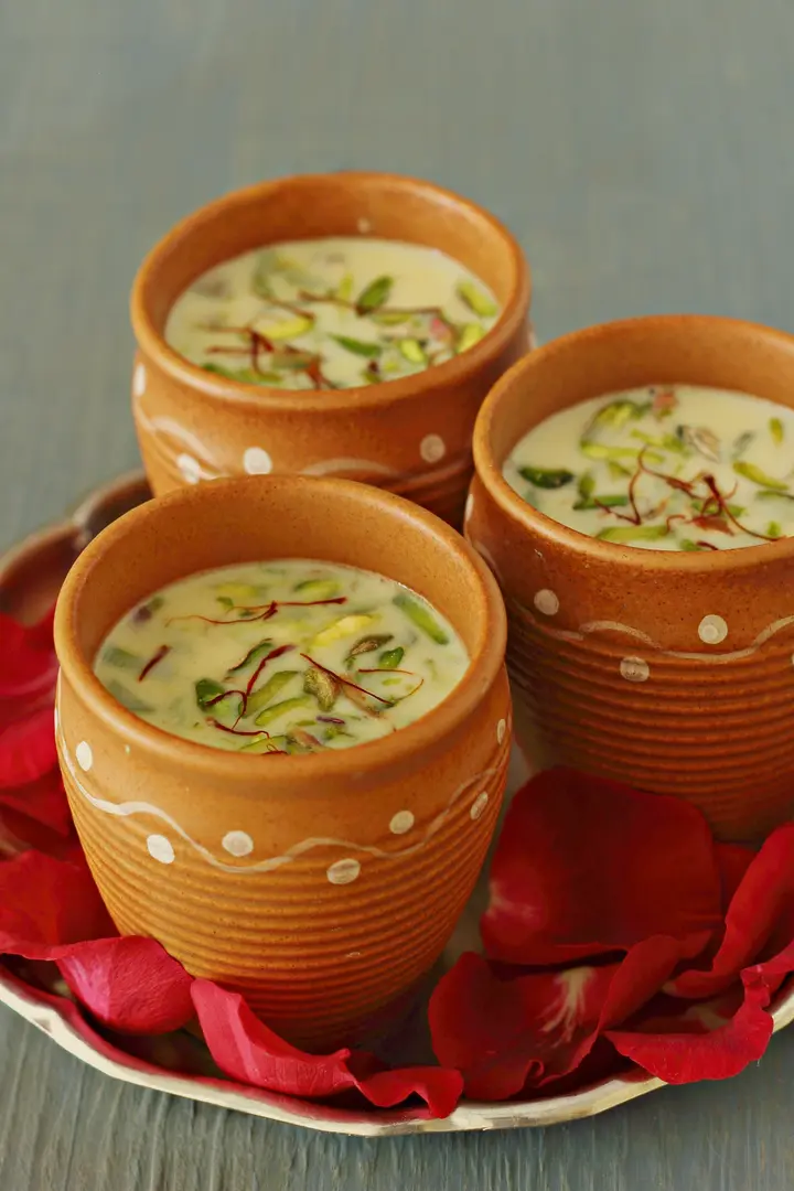 Thandai in clay cups garnished with nuts and saffron