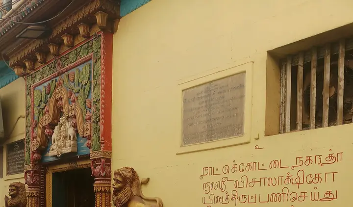 सिंह-आकृतियों वाला विशालाक्षी मंदिर का रंगीन प्रवेश द्वार, पास में दीवार की पट्टिका और नगरत्तार समुदाय का तमिल शिलालेख